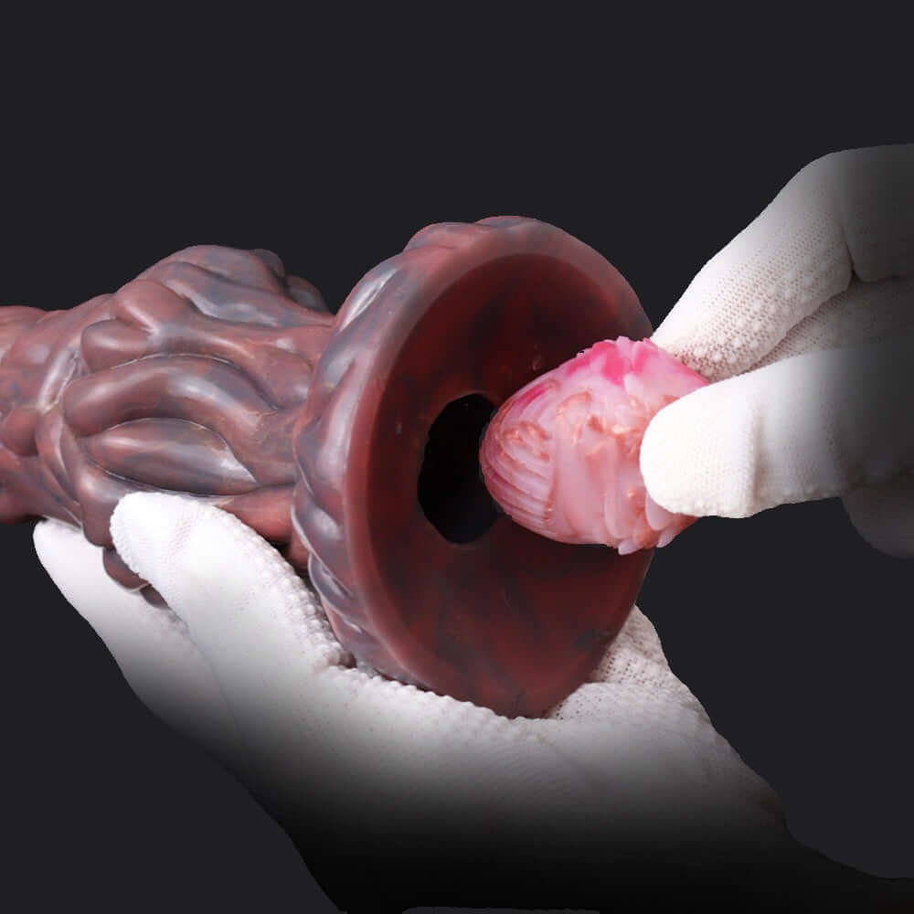 Close-up of hands holding a Pandora Ovipositor Alien Dildo with alien egg attachment, showcasing its texture and design.