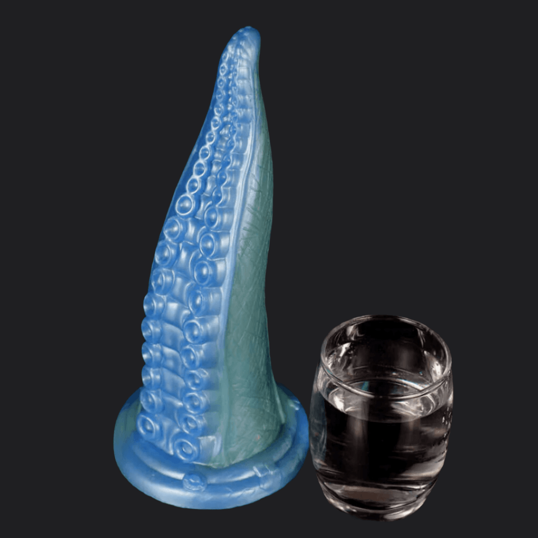 Deep Blue Octopus Tentacle Dildo next to a glass of water against a dark background.