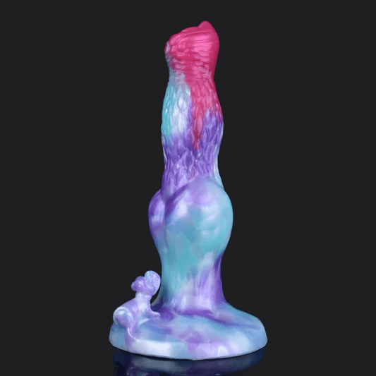 Colorful dragon dildo next to a syringe on a reflective surface, highlighting unique design and features.