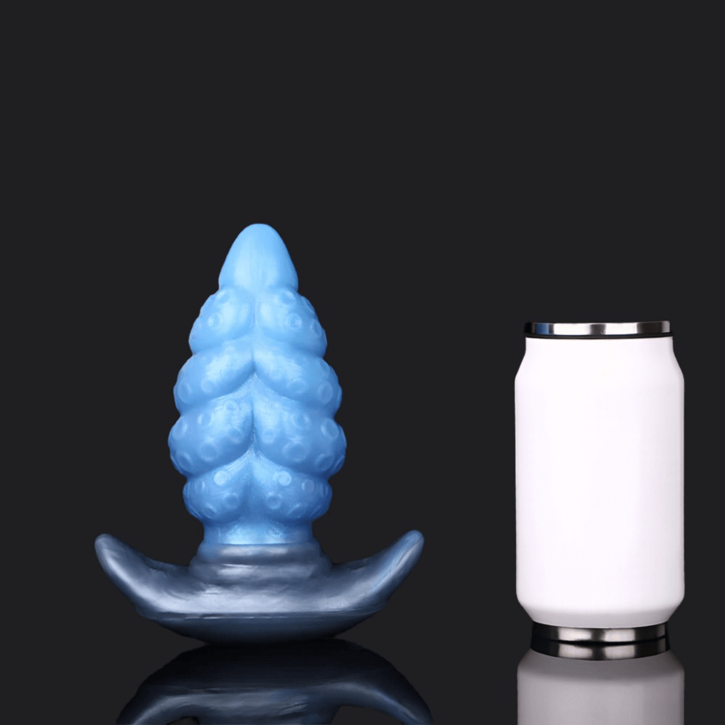 Blue dragon dildo butt plug beside a standard can for size comparison, showcasing a unique textured design.